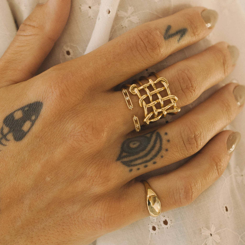 Goudkleurige statement ring gecombineerd met andere ringen aan de hand